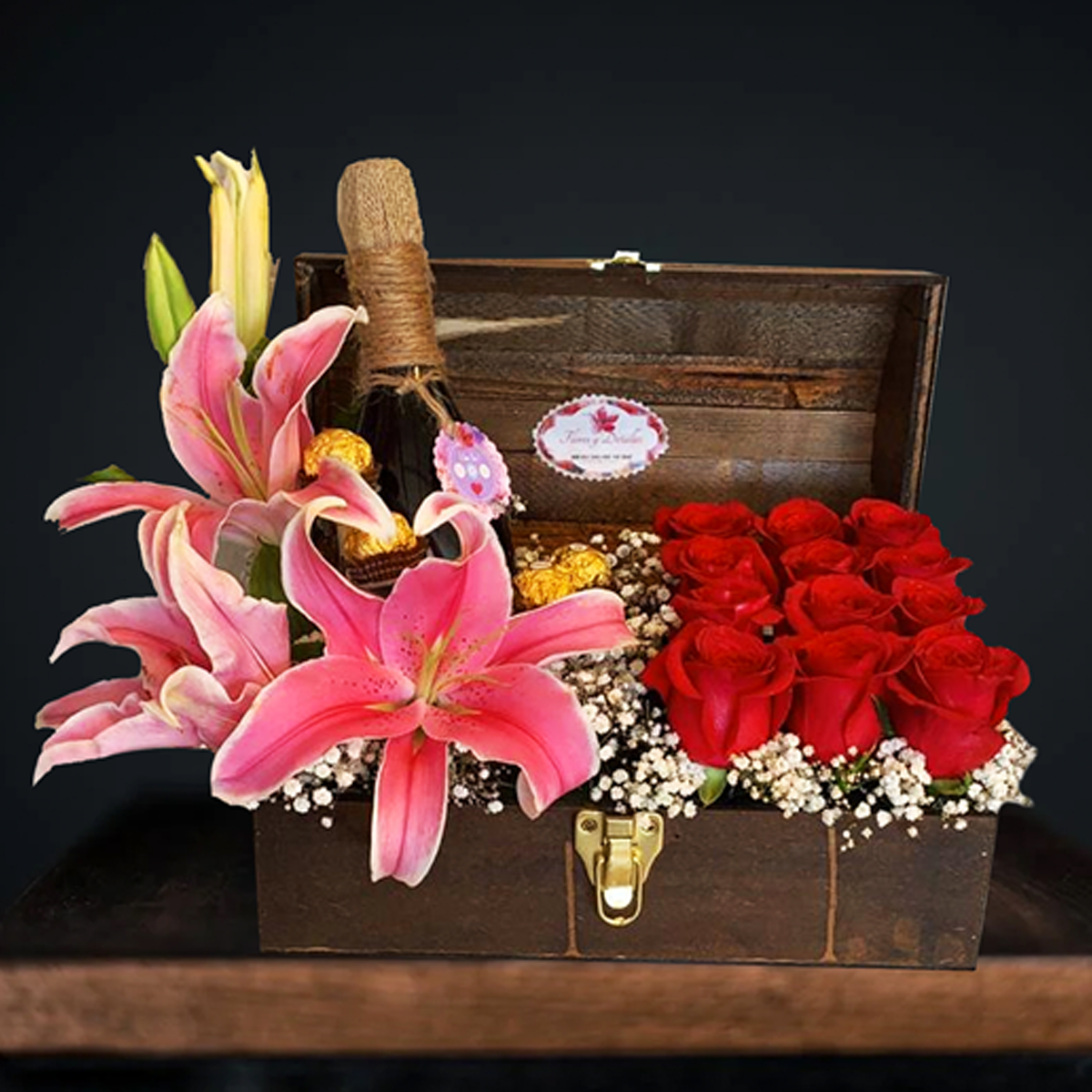 Baúl con 12 rosas, lirios asiáticos, 7 chocolates y botella tipo lambrusco