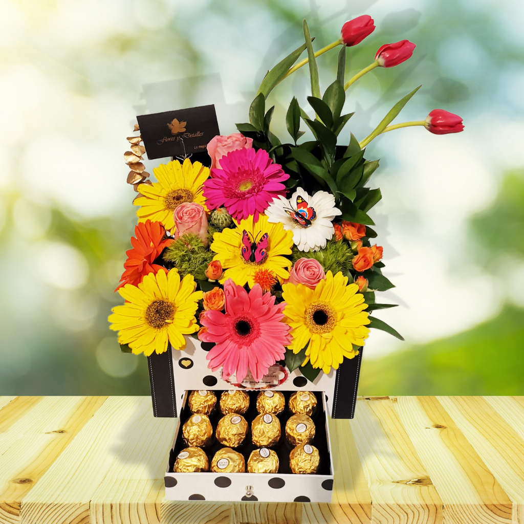 Baúl con cajón con 12 chocolates Ferrero, gerberas, tulipanes, rosas, mini rosas y follajes finos.