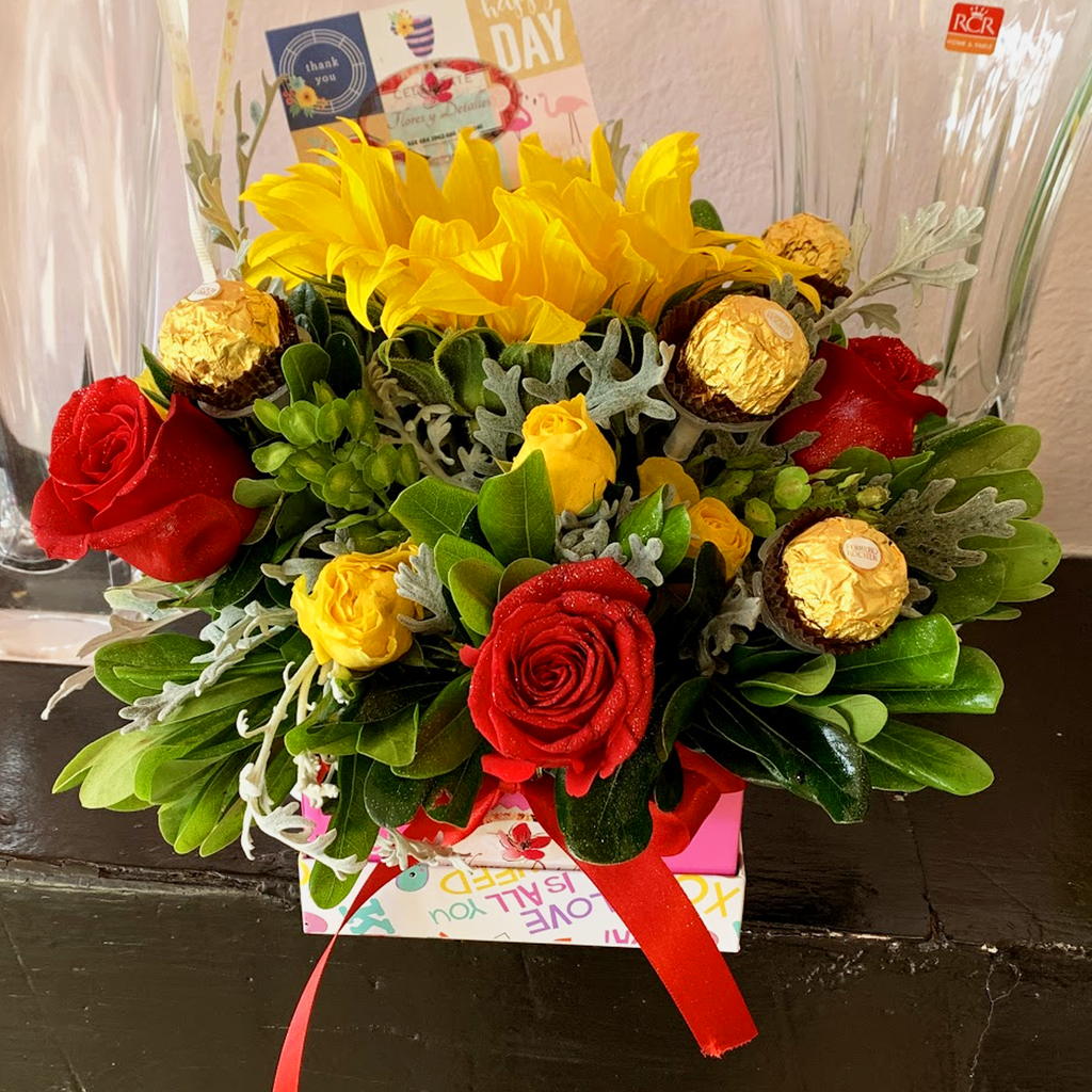 Caja con un Girasol, 4 rosas, tres chocolates y flor variada.